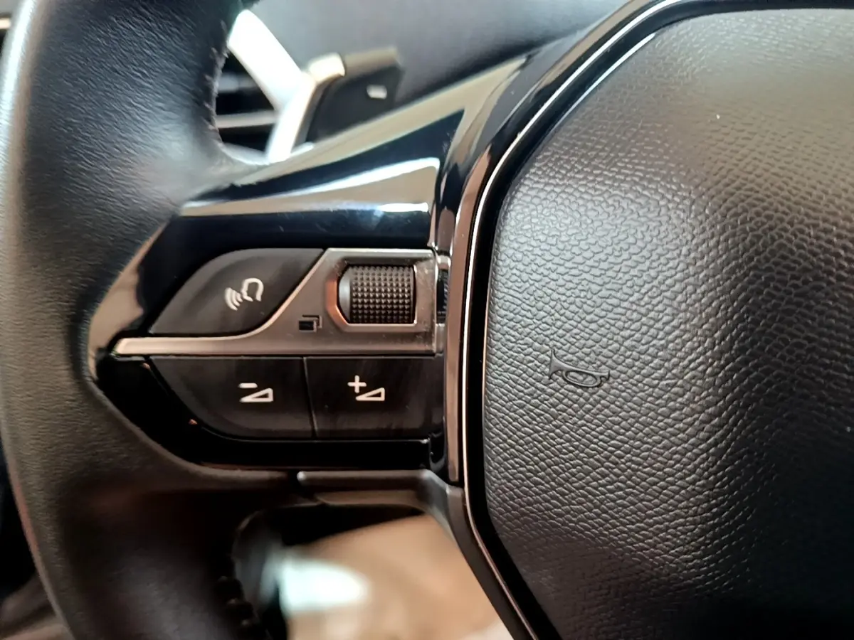 Gros plan sur les commandes gauche du volant cuir noir du Peugeot 5008 gris foncé, version 2020 Active Business.