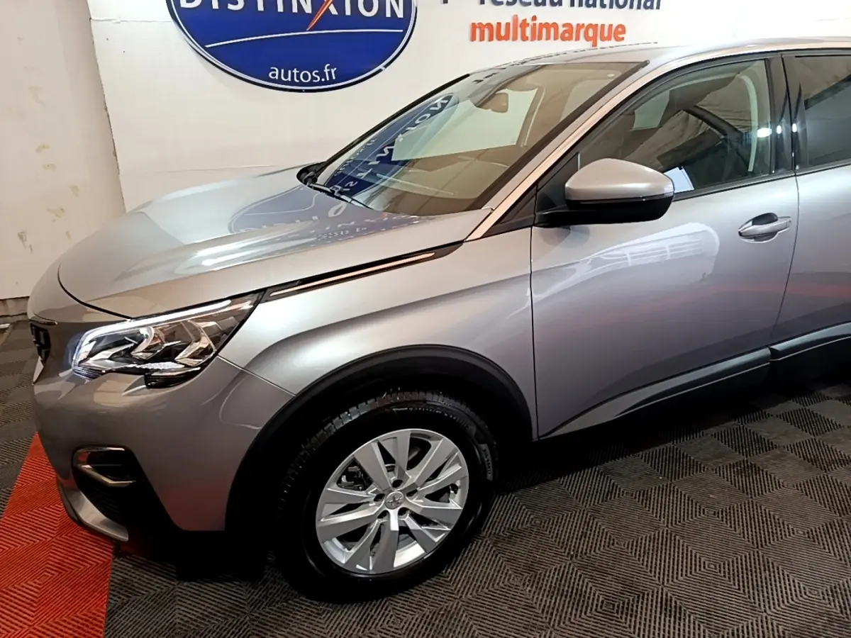 Vue 3/4 avant droit d’un Peugeot 5008 gris foncé avec jantes alliage et rétroviseurs électriques en intérieur showroom.