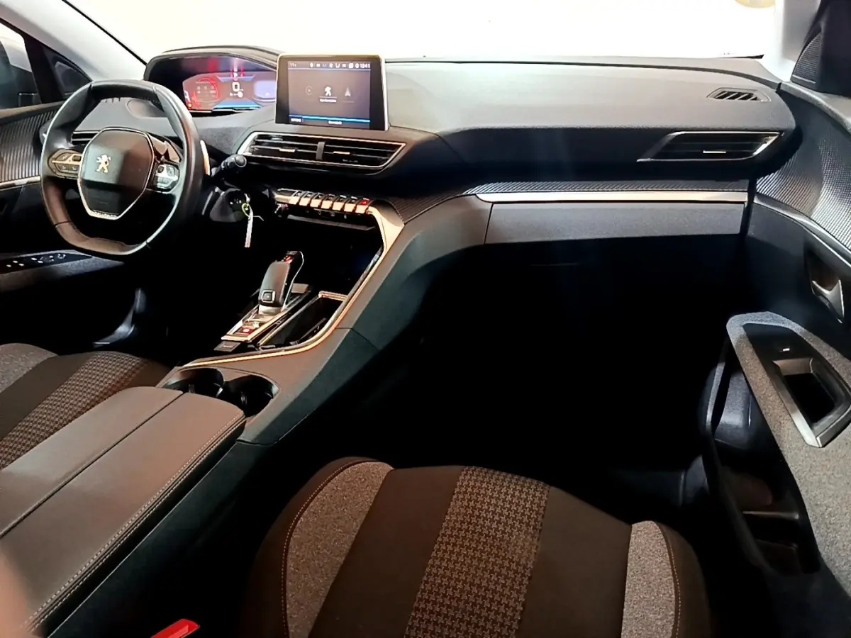 Vue intérieure côté conducteur du tableau de bord noir et gris du Peugeot 5008 avec écran tactile central et volant compact cuir.