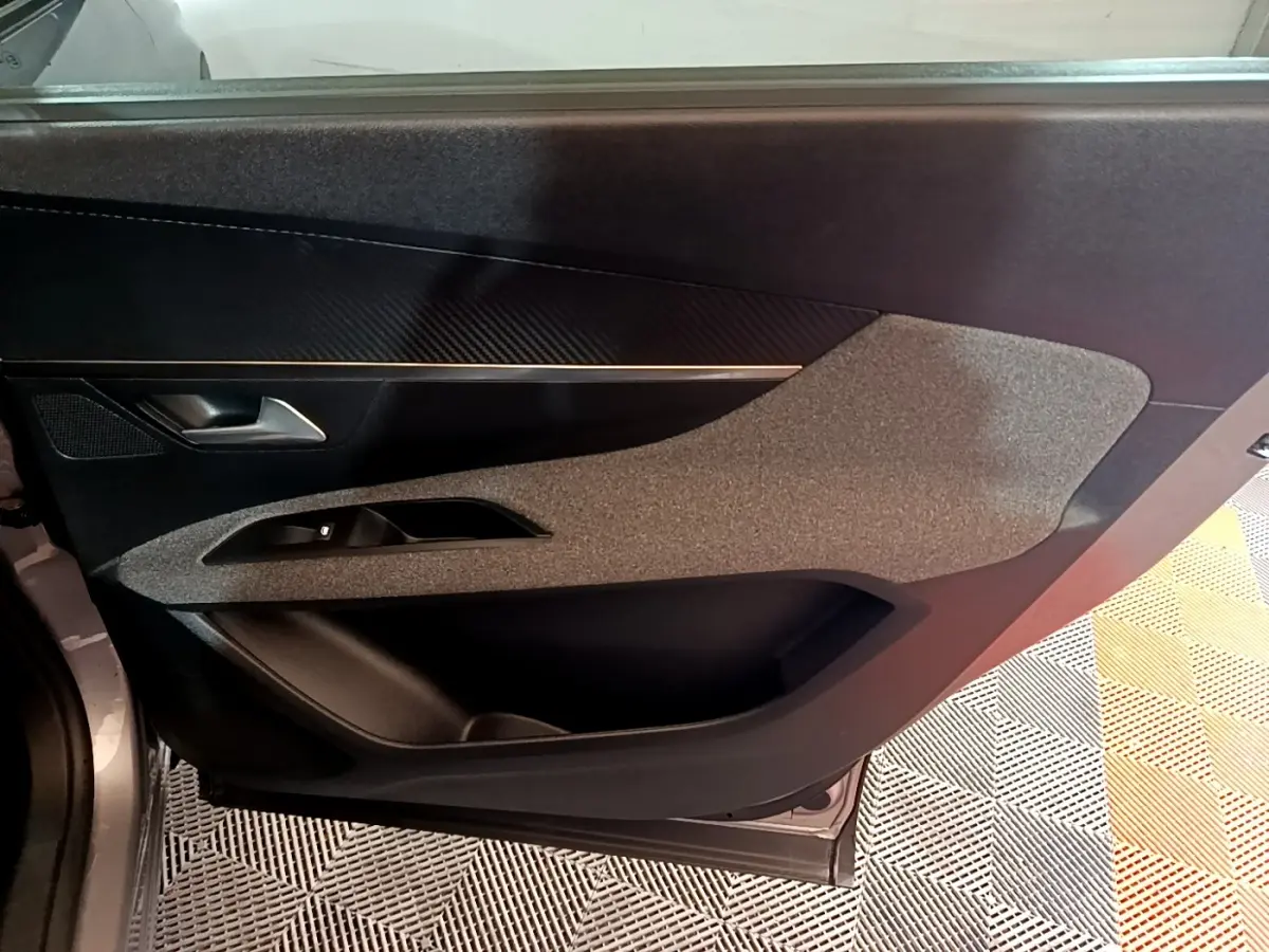 Vue intérieure du panneau de porte côté gauche du Peugeot 5008 gris foncé, avec insert texturé et commande de vitre.