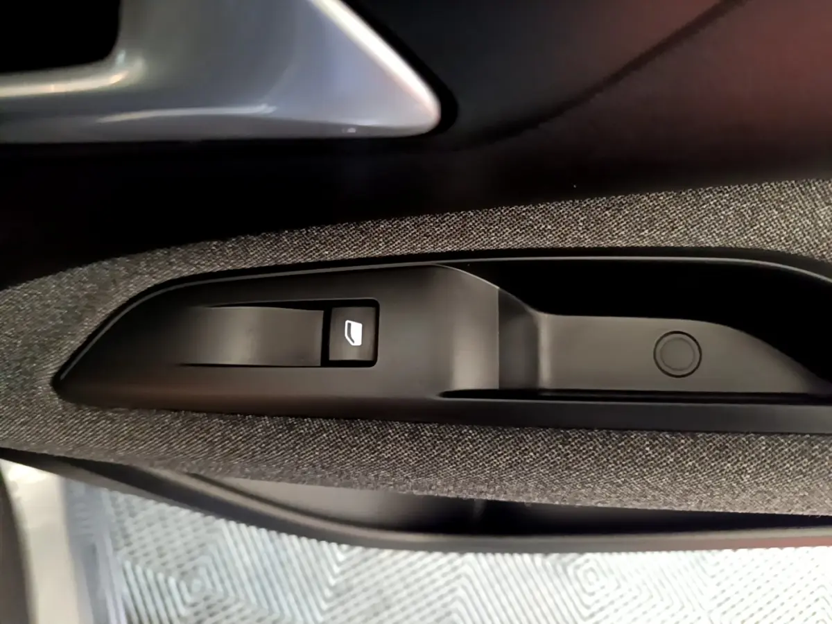 Gros plan sur la commande de lève-vitre côté conducteur du Peugeot 5008 gris foncé, intérieur tissu et plastique.