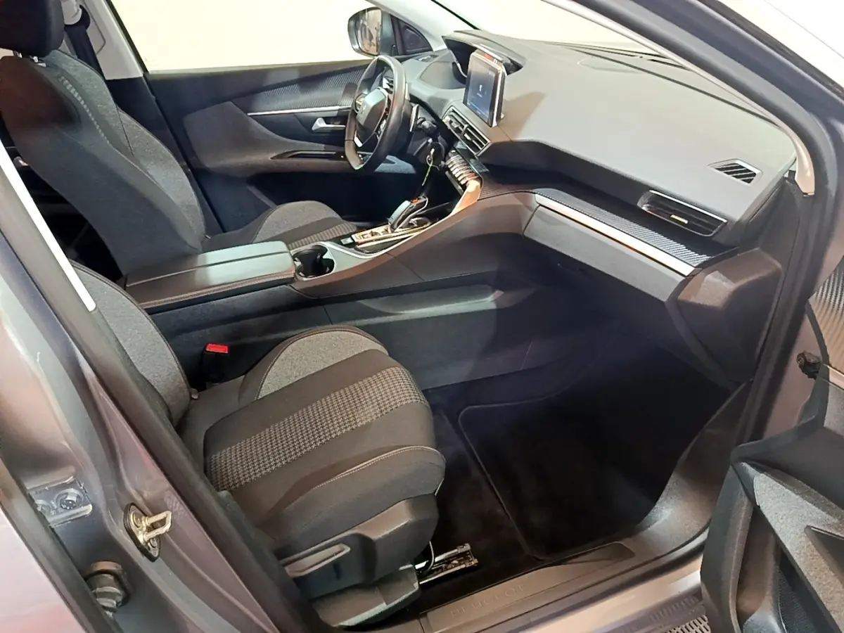 Vue intérieure côté passager du Peugeot 5008 gris foncé, mettant en valeur le tableau de bord moderne avec écran tactile central.