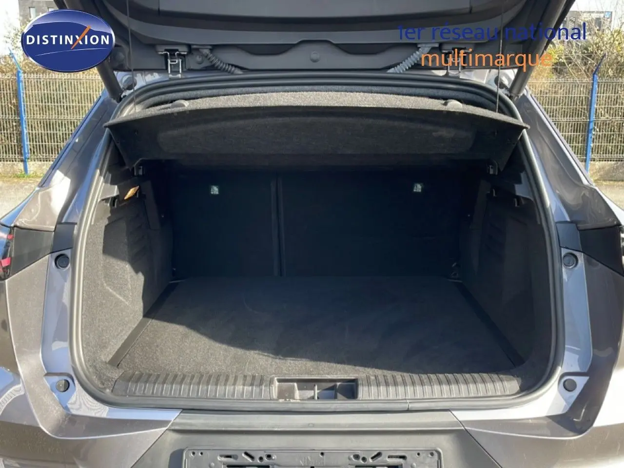 Coffre ouvert vu de l'arrière d'une Renault Symbioz gris cassiopée métal, montrant un espace de chargement spacieux et propre.
