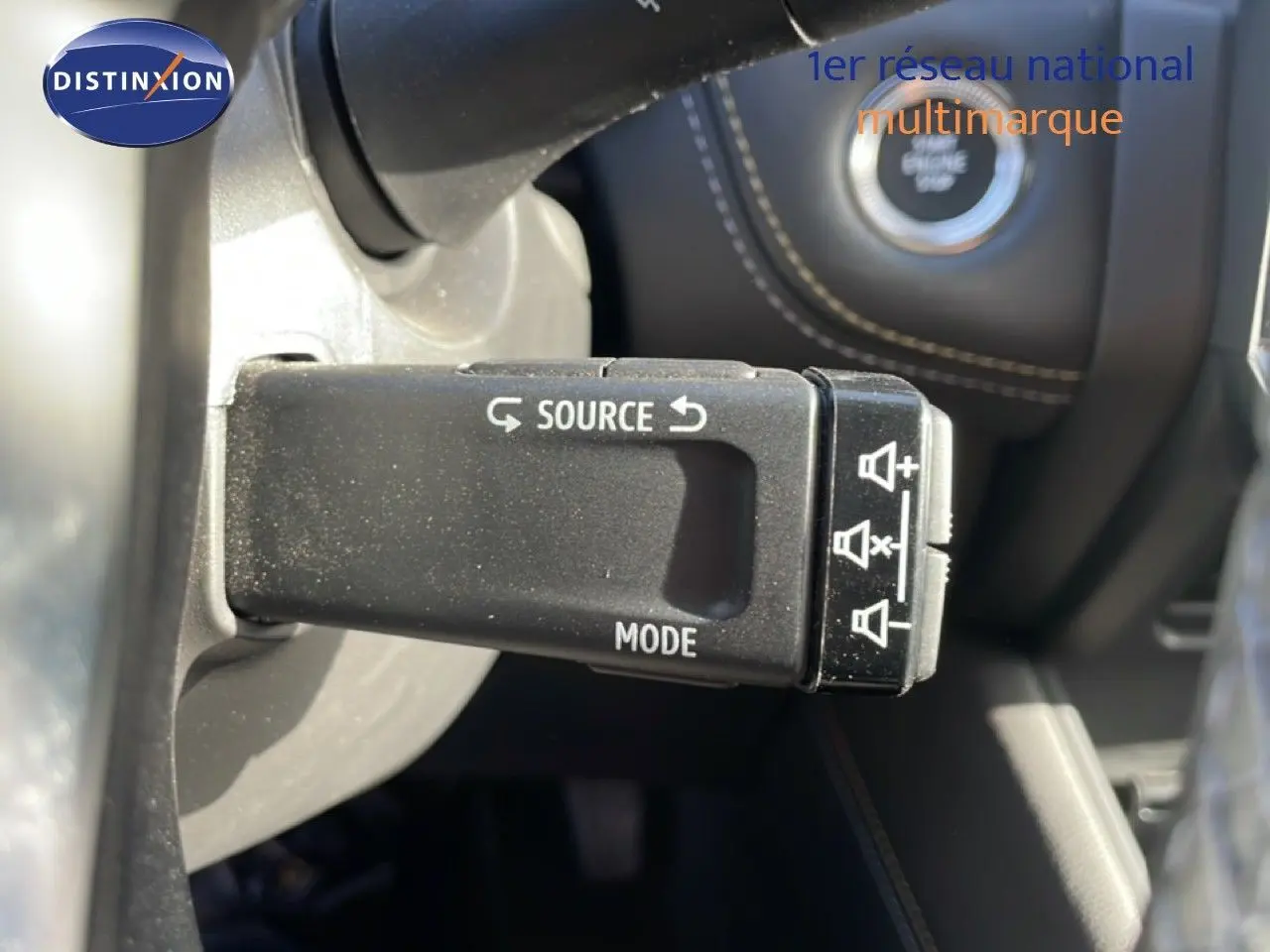 Gros plan sur la commande au volant gauche du Renault Symbioz gris cassiopée, avec boutons source et mode visibles.