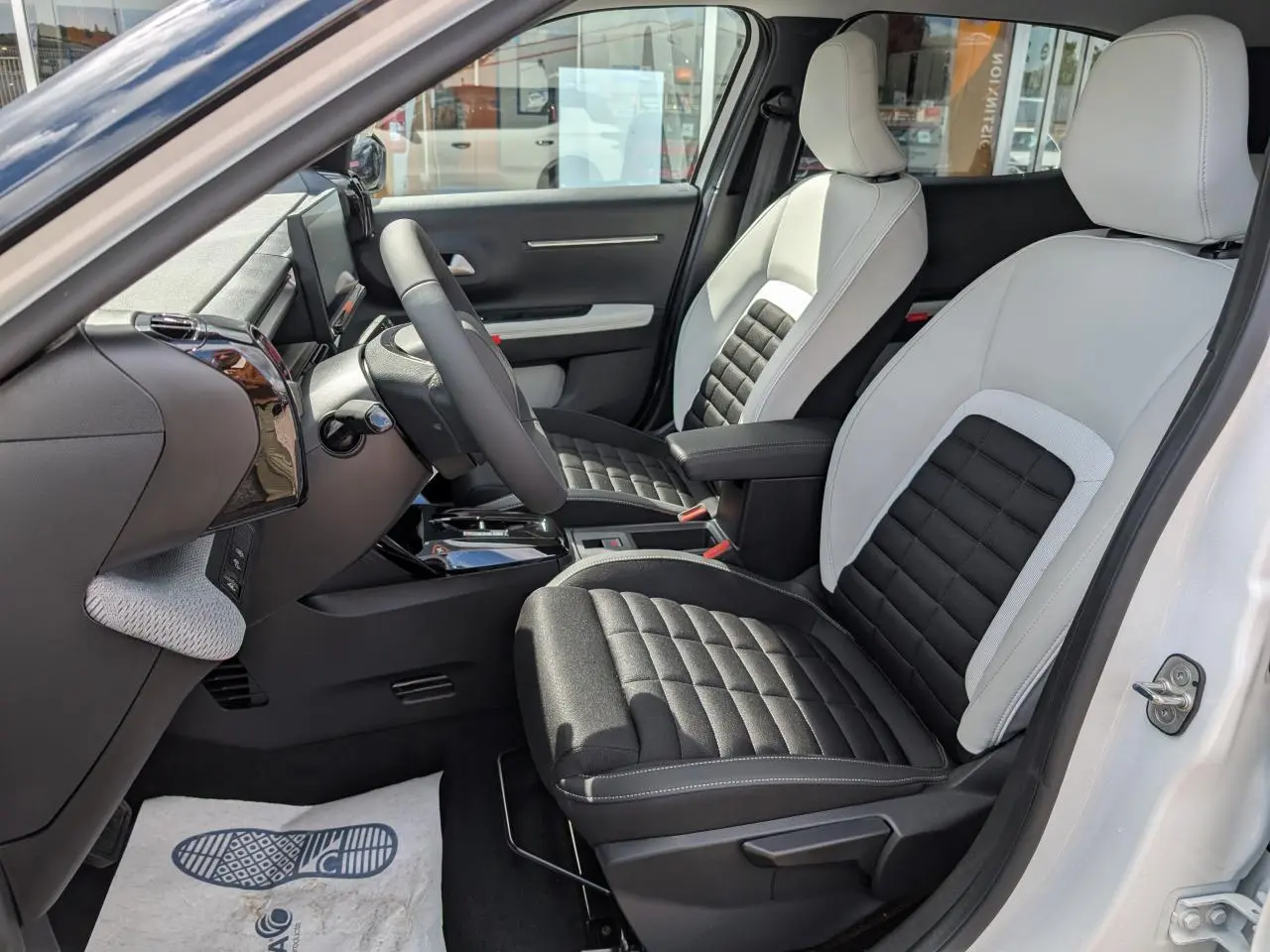 Vue intérieure côté conducteur du Citroën C3 Aircross blanc, sièges bicolores noir et gris avec console centrale et volant multifonctions.