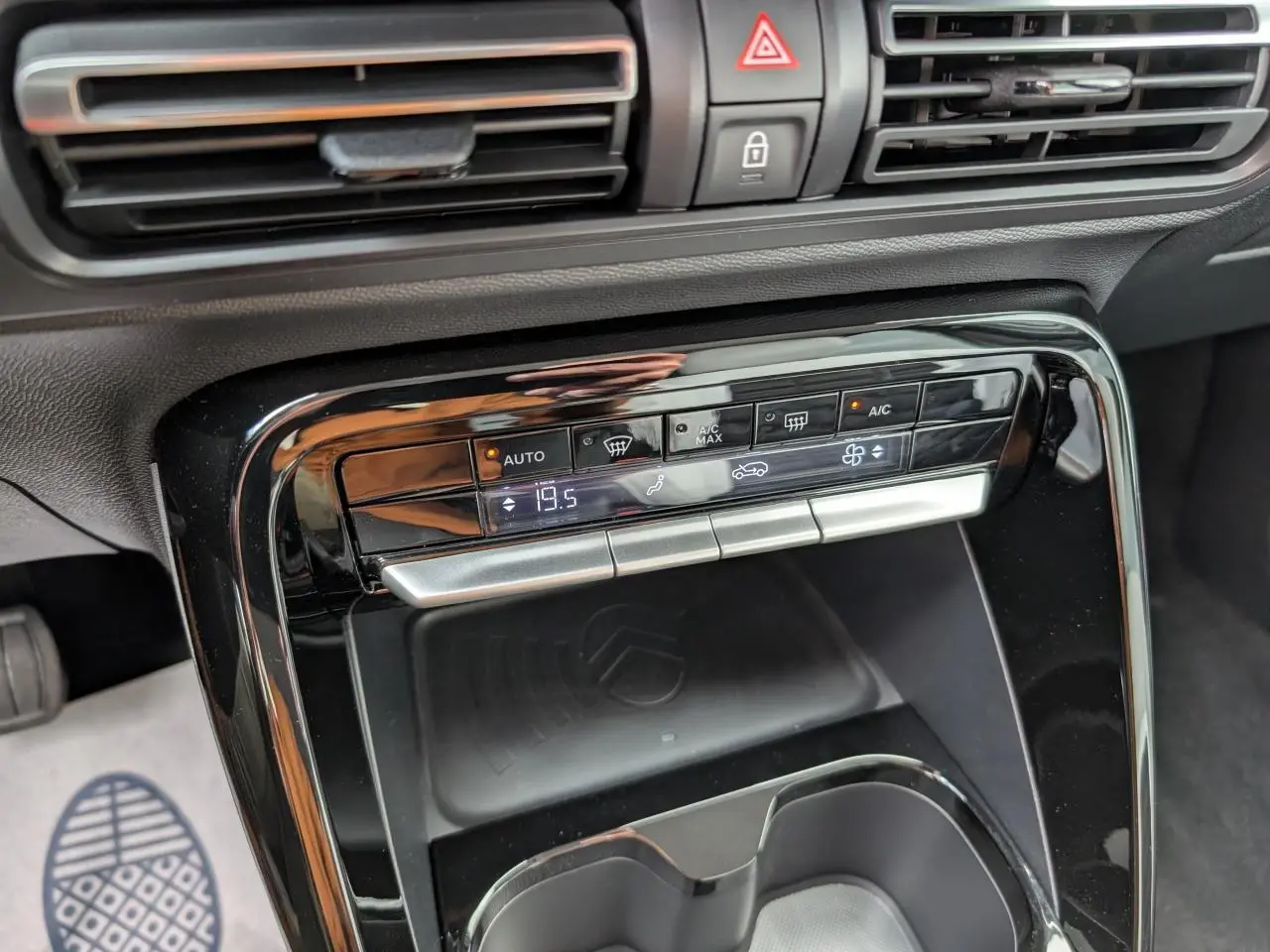Détail de la console centrale noire brillante avec commandes climatisation et espace de recharge sans fil dans une Citroën C3 Aircross blanche.