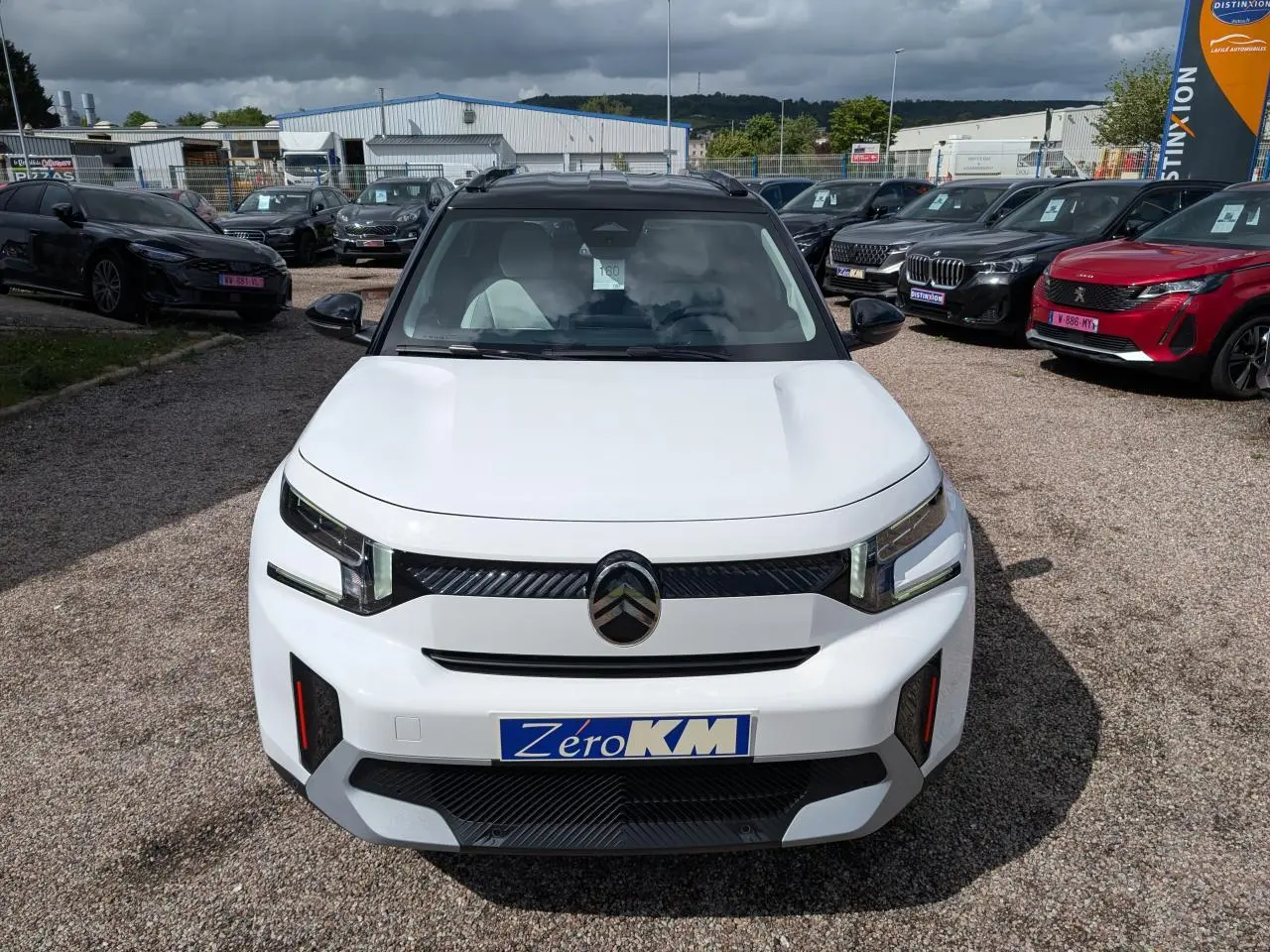 Vue avant d'un Citroën C3 Aircross blanc Banquise avec toit noir et détails noirs brillants sur un parking.