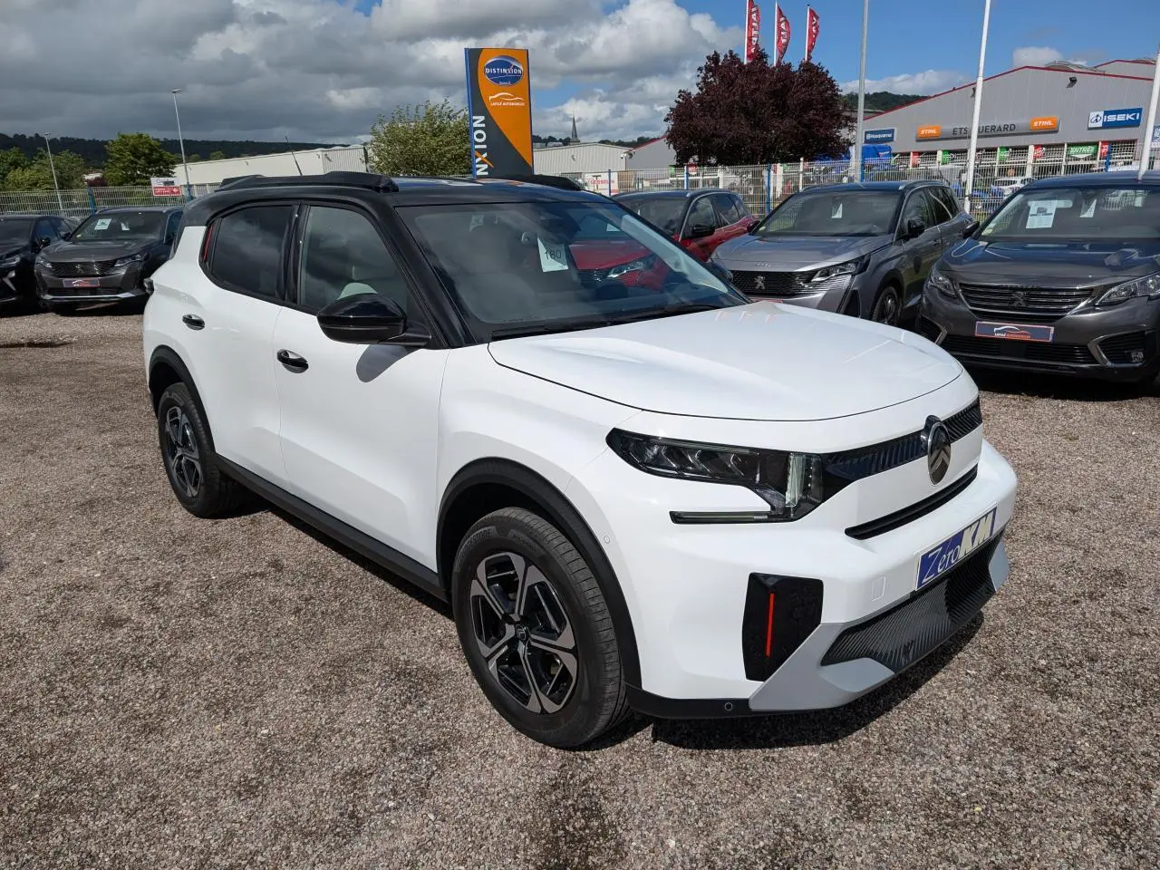 Vue 3/4 avant droite d'un Citroën C3 Aircross blanc avec toit noir et jantes alliage 17'' sur parking extérieur.