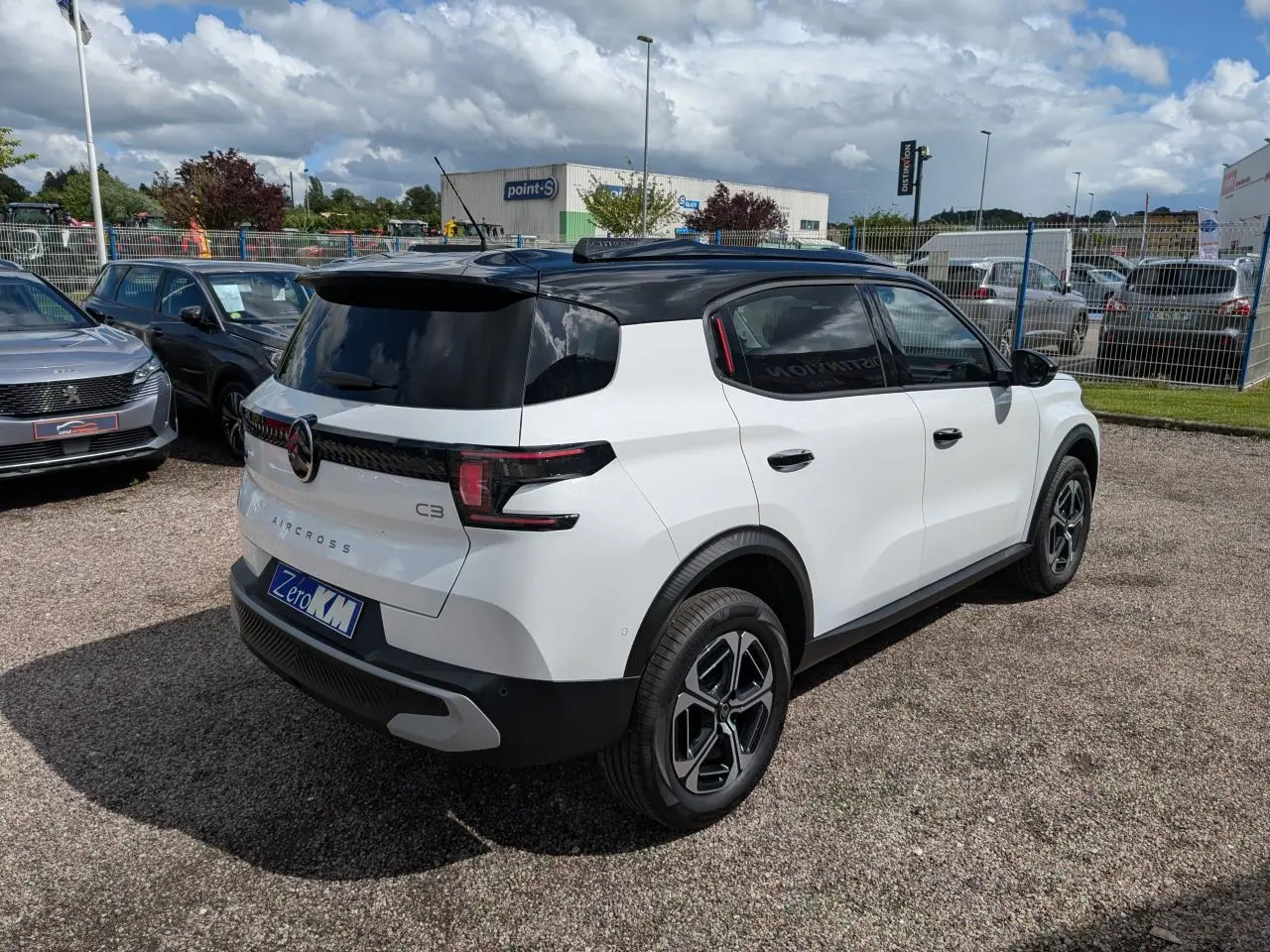 Vue 3/4 arrière droite d'un Citroën C3 Aircross blanc avec toit noir et jantes alliage 17 pouces.