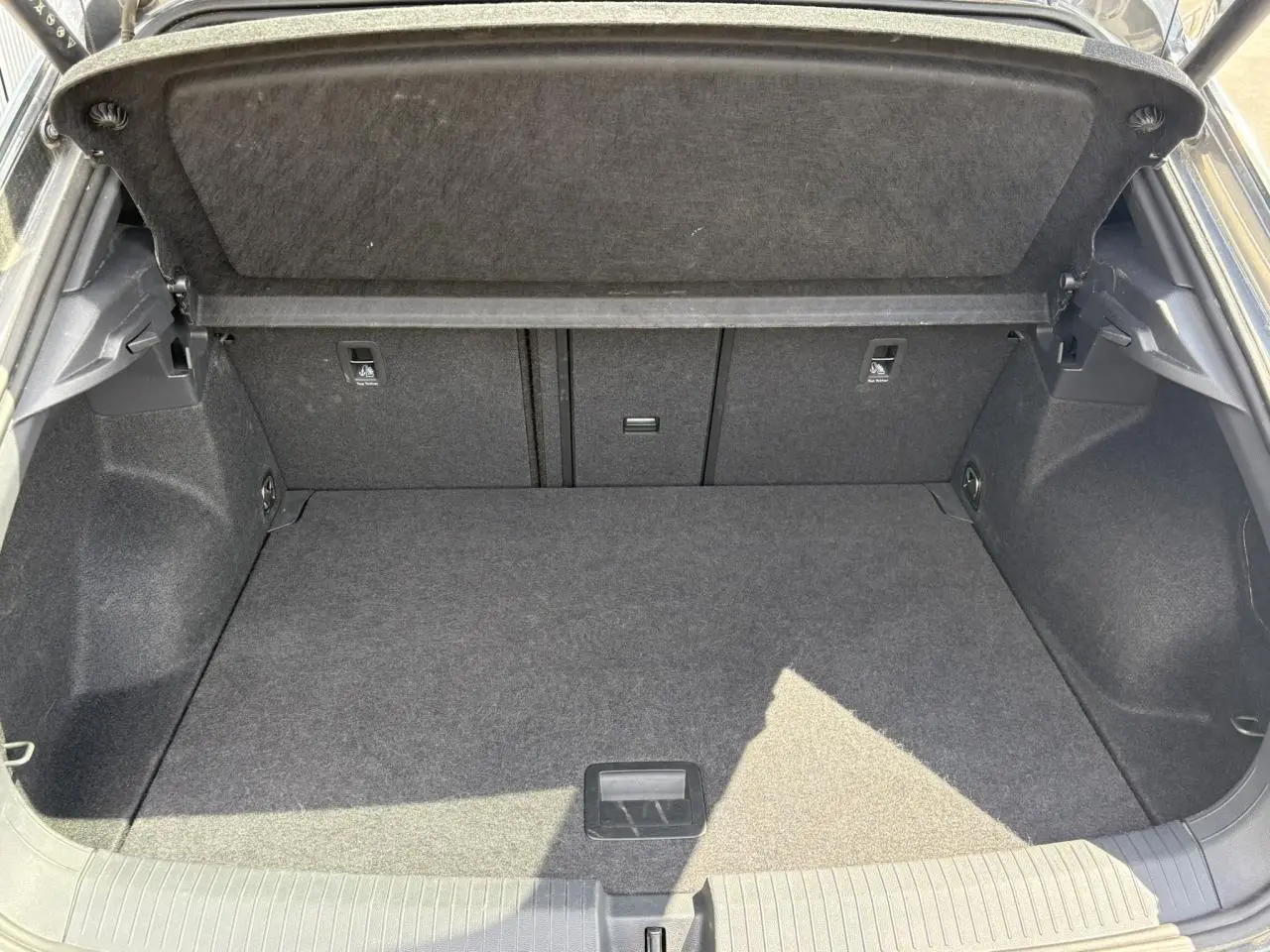 Coffre ouvert du Volkswagen T-Roc gris Indium, montrant un espace de chargement propre et bien agencé.