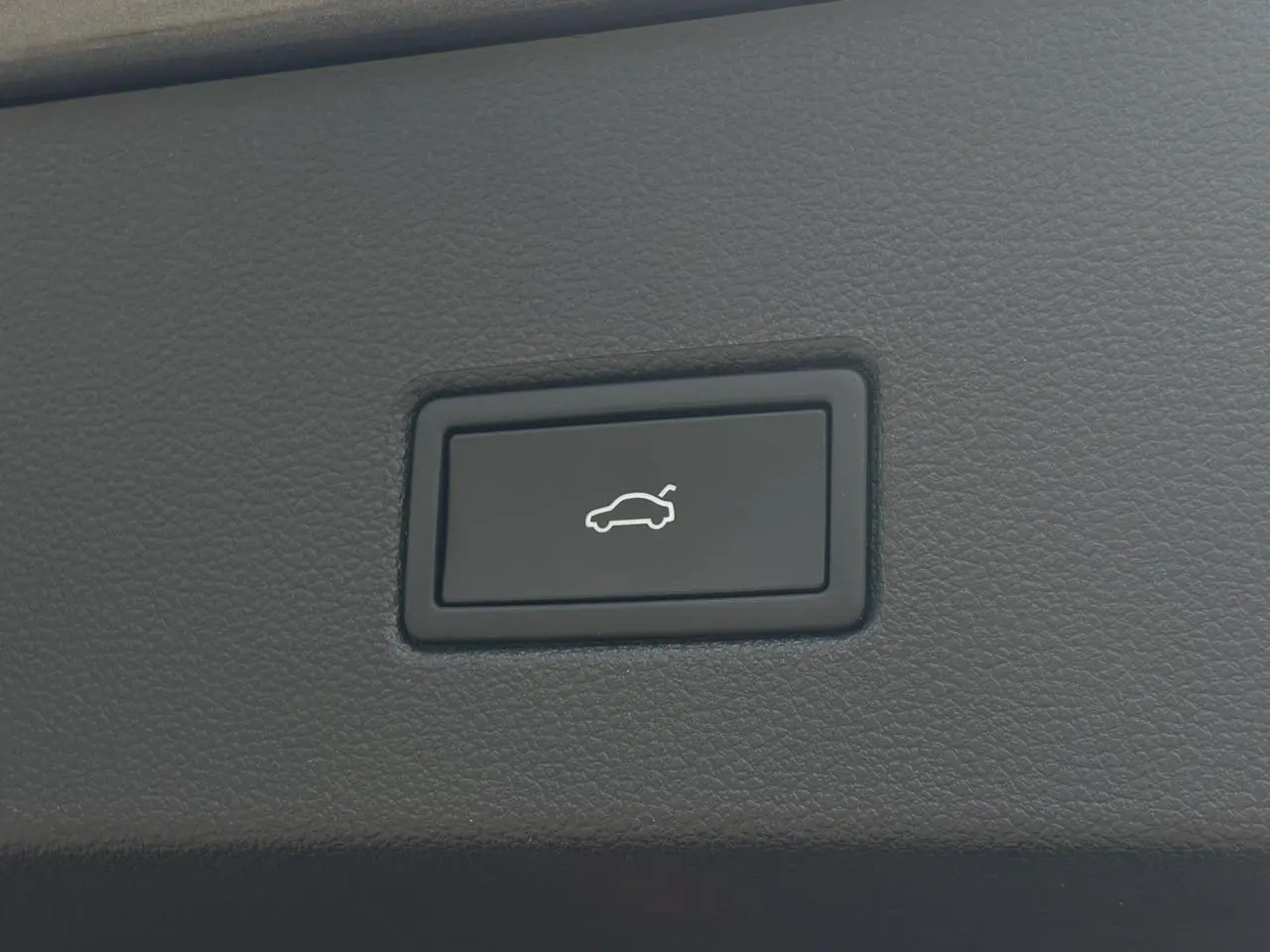 Bouton noir d'ouverture électrique du hayon sur tableau de bord en cuir gris du Volkswagen T-Roc 2025.
