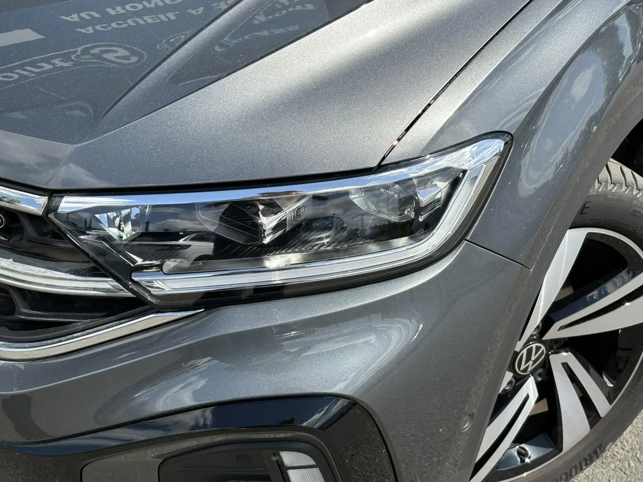 Gros plan sur le phare Matrix LED et la jante alliage 18" du côté avant droit du Volkswagen T-Roc gris Indium.