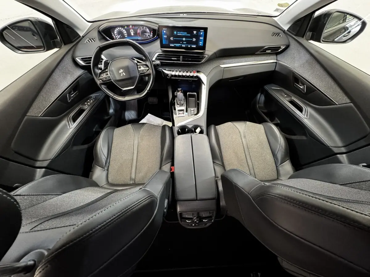 Vue intérieure avant du Peugeot 5008 noir 2022, avec tableau de bord numérique et écran tactile central lumineux.