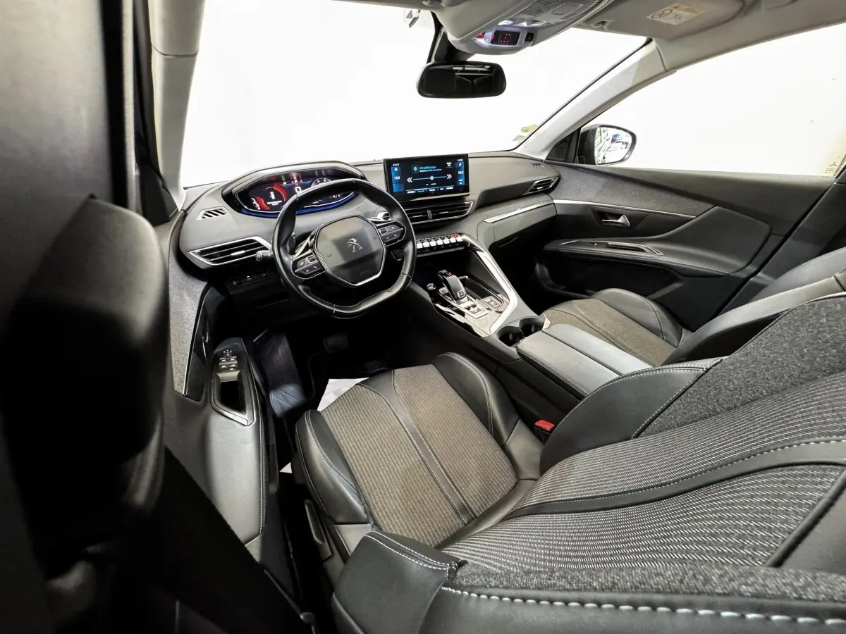 Vue intérieure côté conducteur du Peugeot 5008 noir, mettant en valeur le tableau de bord numérique et l'écran tactile central.