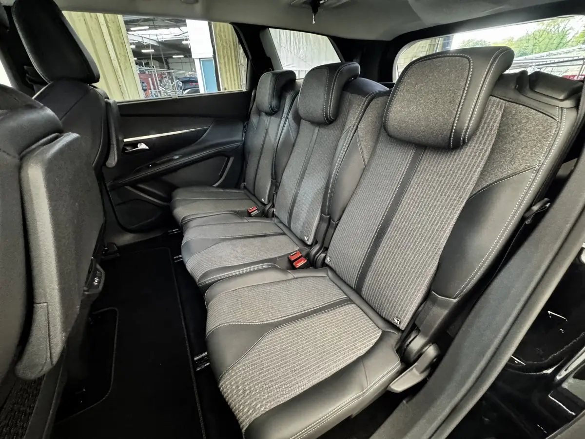 Vue latérale intérieure sur la deuxième rangée de sièges gris et noirs du Peugeot 5008 noir, version 2022 Allure Pack.