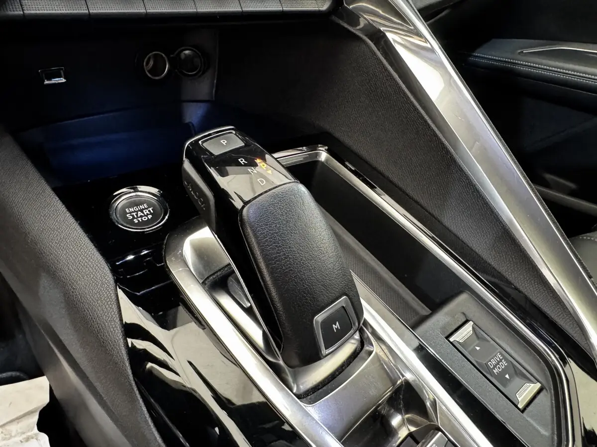 Gros plan sur la console centrale noire du Peugeot 5008 2022, avec levier de boîte auto et bouton start/stop.