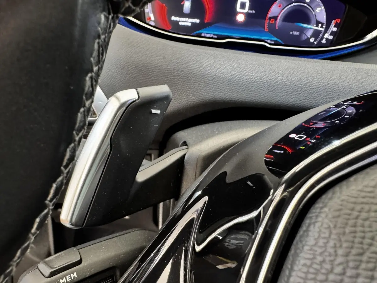 Détail du levier de vitesses et du tableau de bord numérique du Peugeot 5008 noir, vue rapprochée côté conducteur.