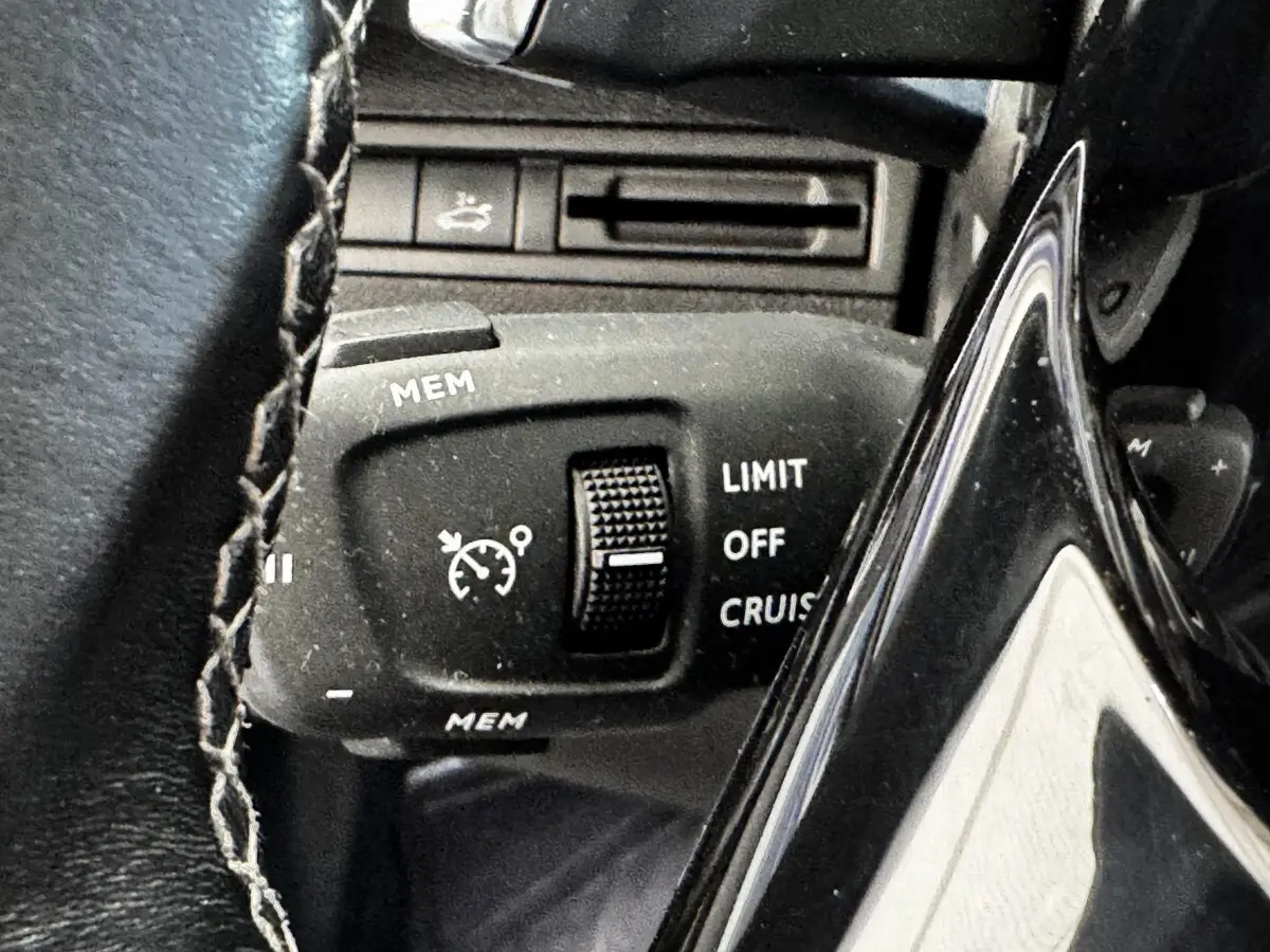 Gros plan sur la commande de régulateur de vitesse au volant cuir du Peugeot 5008 noir, version Allure Pack 2022.
