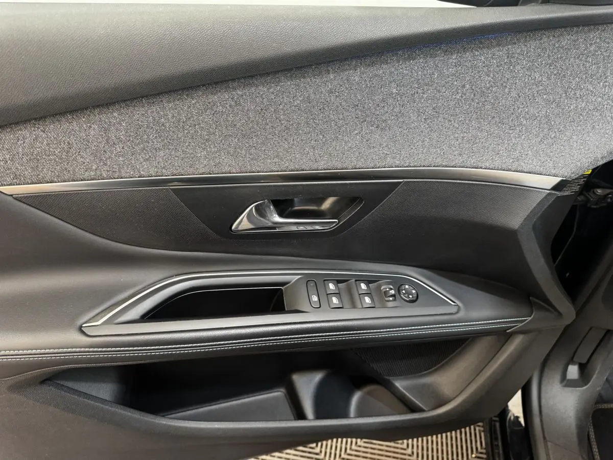 Vue rapprochée de la porte côté conducteur du Peugeot 5008 noir, avec commandes de vitres et poignée argentée.