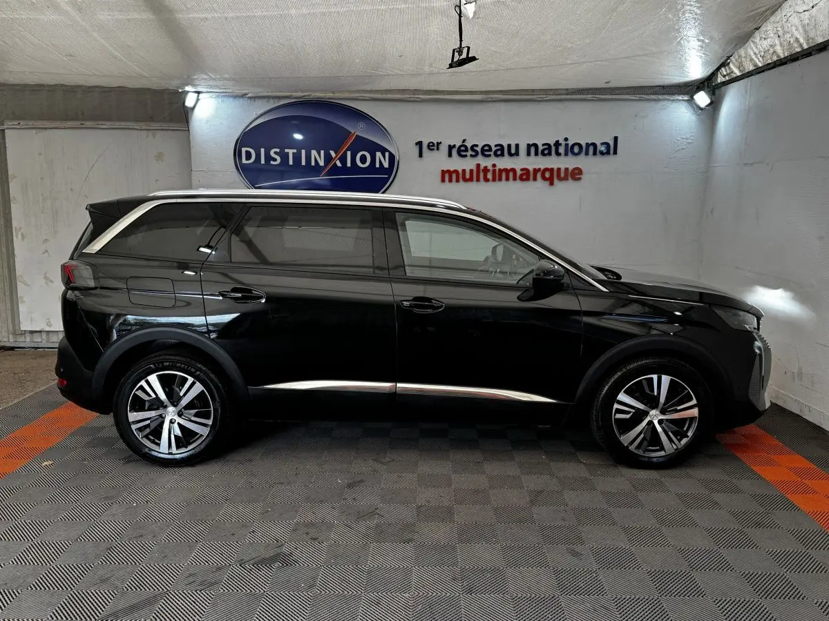 Profil droit d'un Peugeot 5008 noir 2022 avec jantes alliage et vitres teintées dans un showroom.