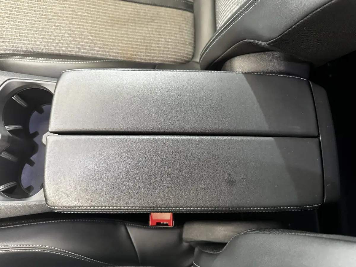 Vue rapprochée du couvercle de la console centrale en cuir noir avec surpiqûres blanches dans l’habitacle d’un Peugeot 5008.
