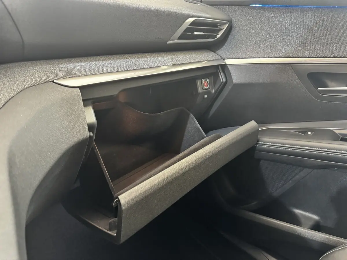 Gros plan sur la boîte à gants ouverte côté passager du Peugeot 5008 noir, soulignant les finitions intérieures modernes.