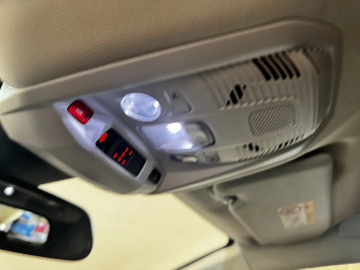 Plafonnier intérieur avec éclairage LED et bouton d'appel d'urgence dans un Peugeot 5008 noir, vue vers le toit côté conducteur.