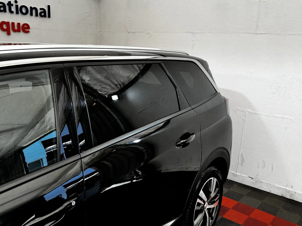 Vue côté droit arrière d’un Peugeot 5008 noir, mettant en valeur les vitres teintées et les jantes alliage modernes.