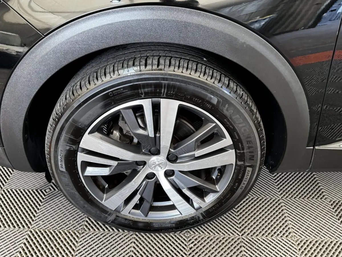 Gros plan sur la roue avant droite noire d’un Peugeot 5008 2022 avec jante alliage bicolore et pneu Michelin.