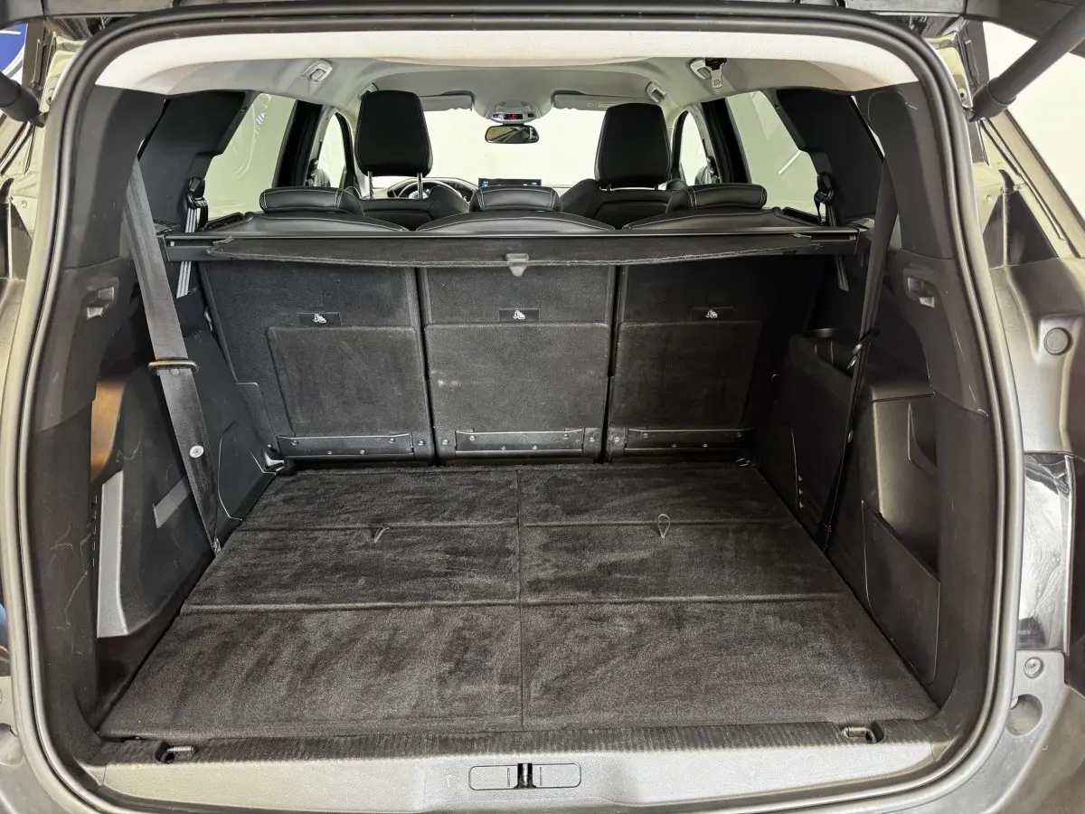 Coffre ouvert vu de l'arrière d'un Peugeot 5008 noir, avec sièges rabattus et plancher plat.