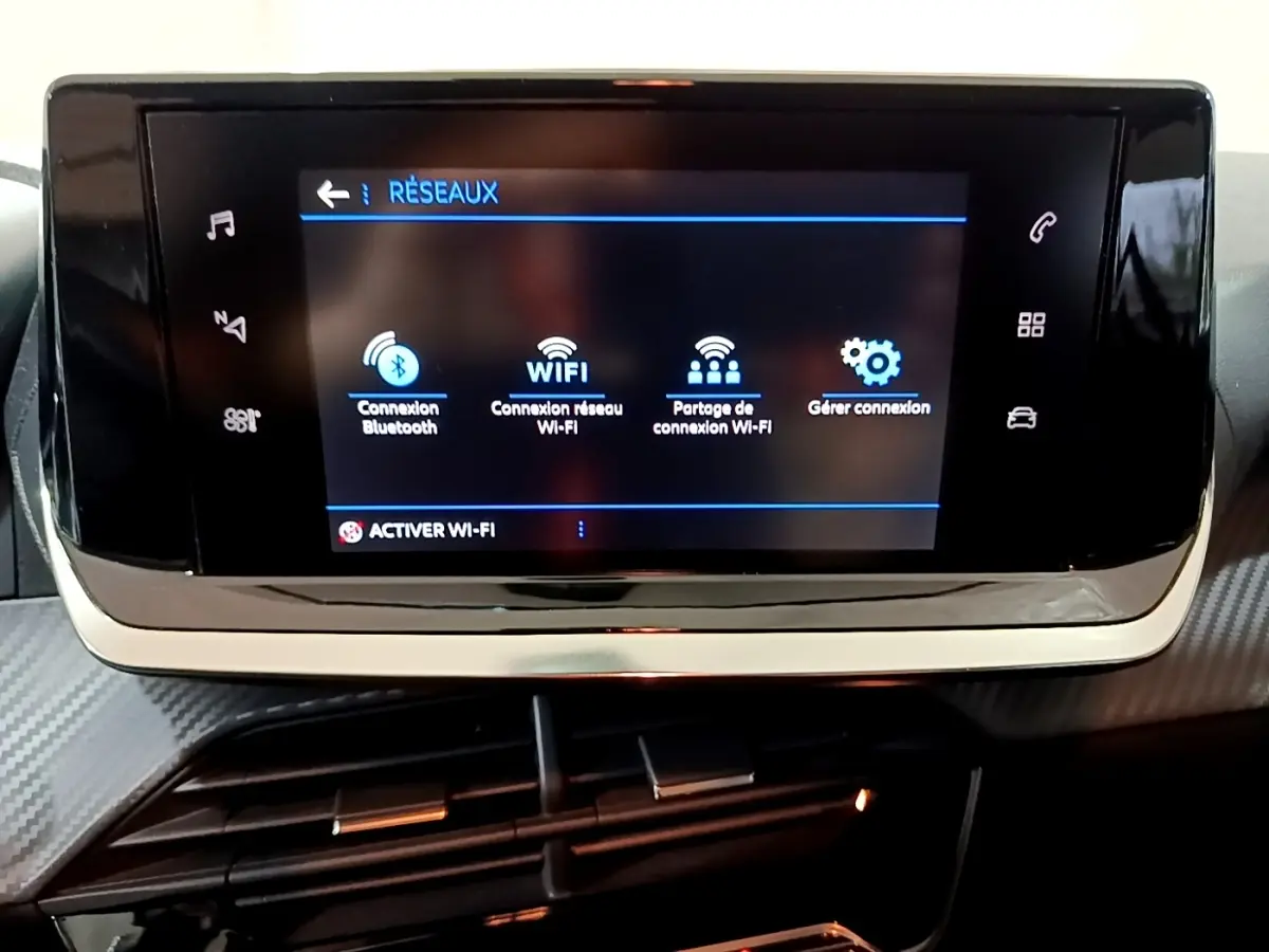 Écran tactile central de la Peugeot 208 blanc, affichant les options de connexion Bluetooth et Wi-Fi, vue de face.