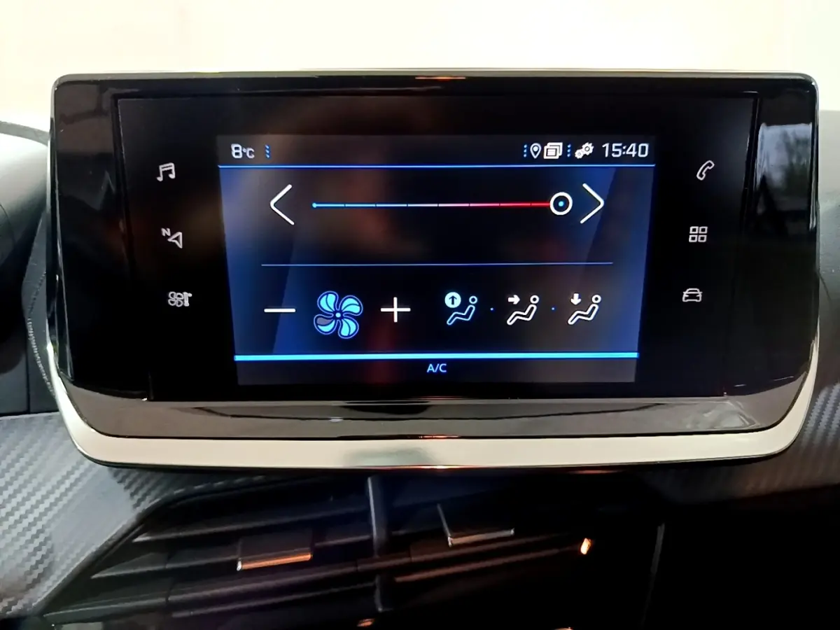 Écran tactile central de la Peugeot 208 blanc, affichant les réglages de climatisation intérieure.