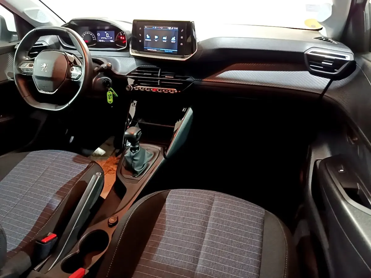 Vue intérieure avant droite du tableau de bord et console centrale de la Peugeot 208 blanche avec écran tactile et boîte manuelle.