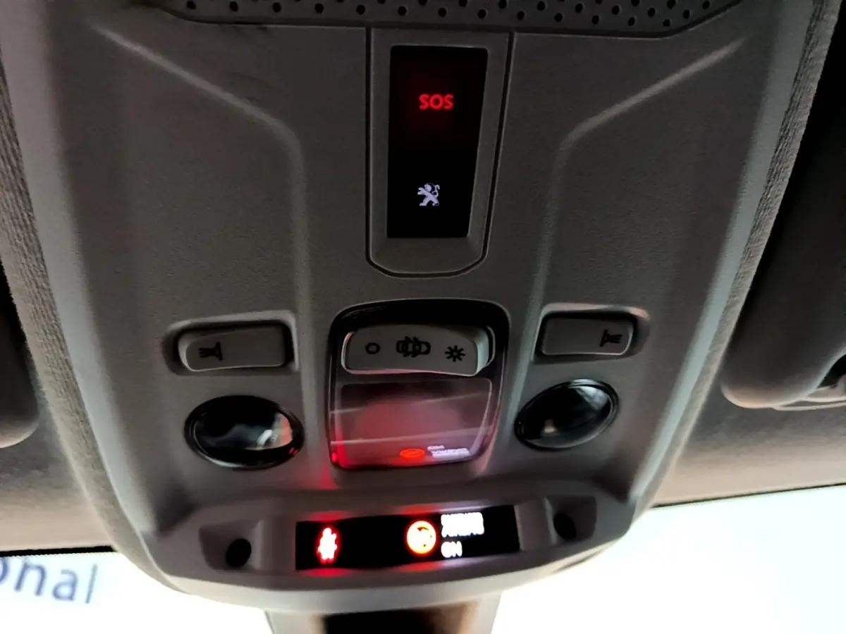 Vue intérieure en gros plan du plafonnier gris avec bouton SOS et éclairage dans une Peugeot 208 blanche.