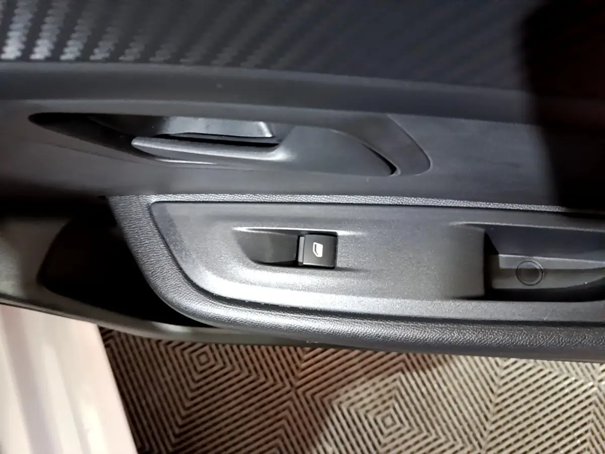 Gros plan sur le bouton de commande de lève-vitre côté conducteur de la Peugeot 208 blanche, intérieur noir.