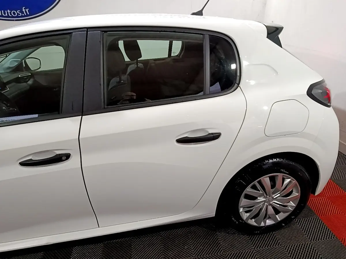 Vue latérale droite d'une Peugeot 208 blanche de 2021, mettant en valeur les poignées noires et les jantes argentées.