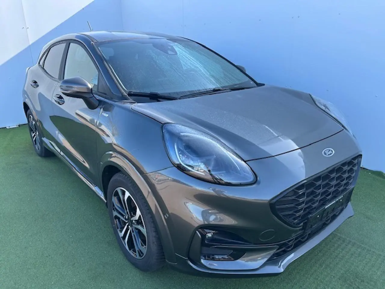 Vue 3/4 avant droit d'un Ford Puma gris magnetic avec calandre noire et jantes alliage 17 pouces.