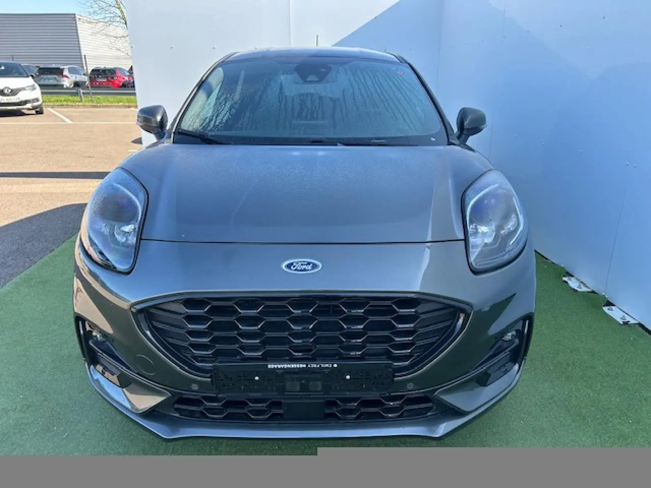 Vue avant rapprochée d’un Ford Puma gris Magnetic 2023 avec calandre noire et phares arrondis.