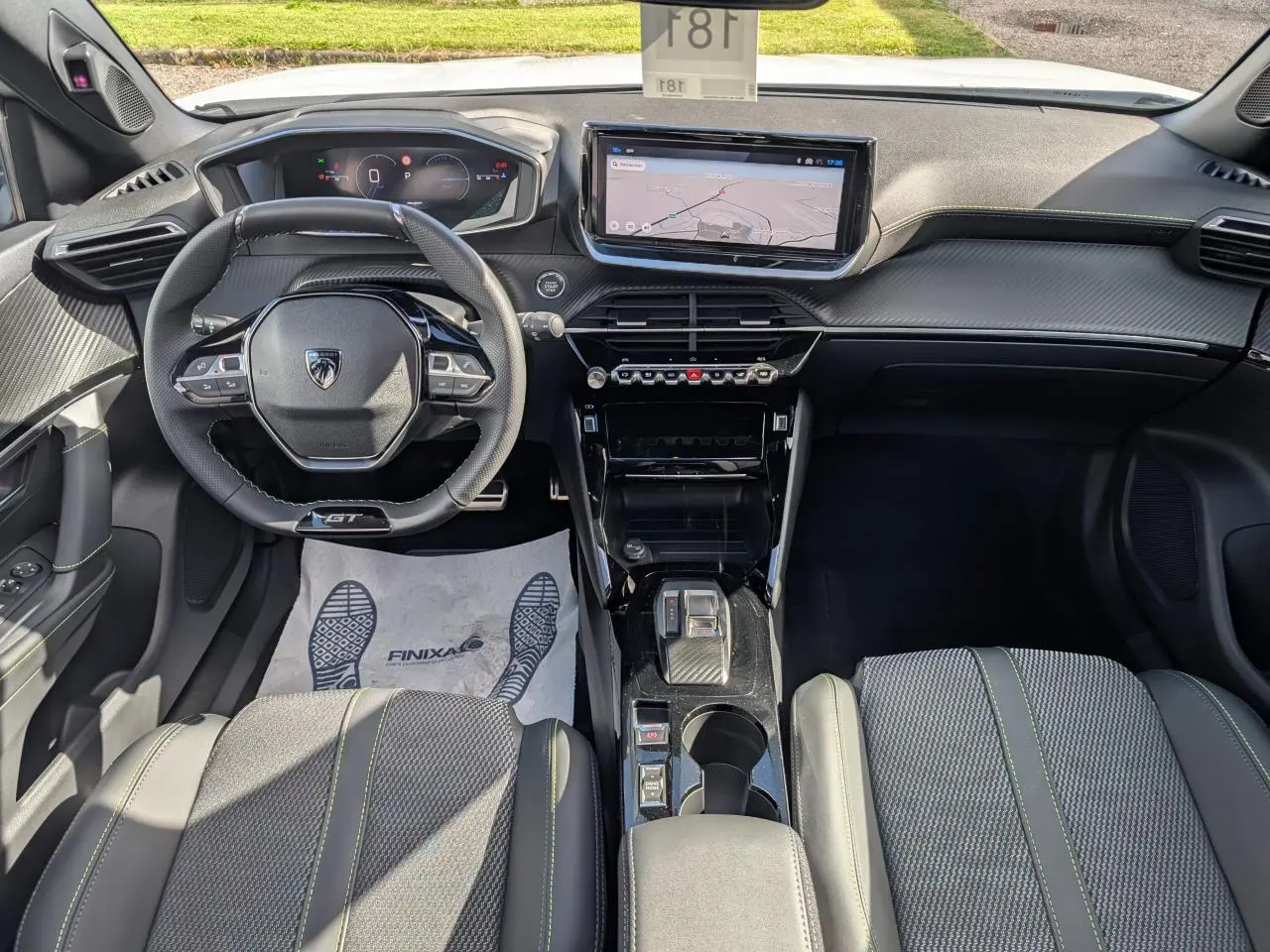 Vue intérieure avant du Peugeot 2008 GT hybride 2026, avec volant compact, écran tactile 10 pouces et sellerie tissu noire à surpiqûres vertes.