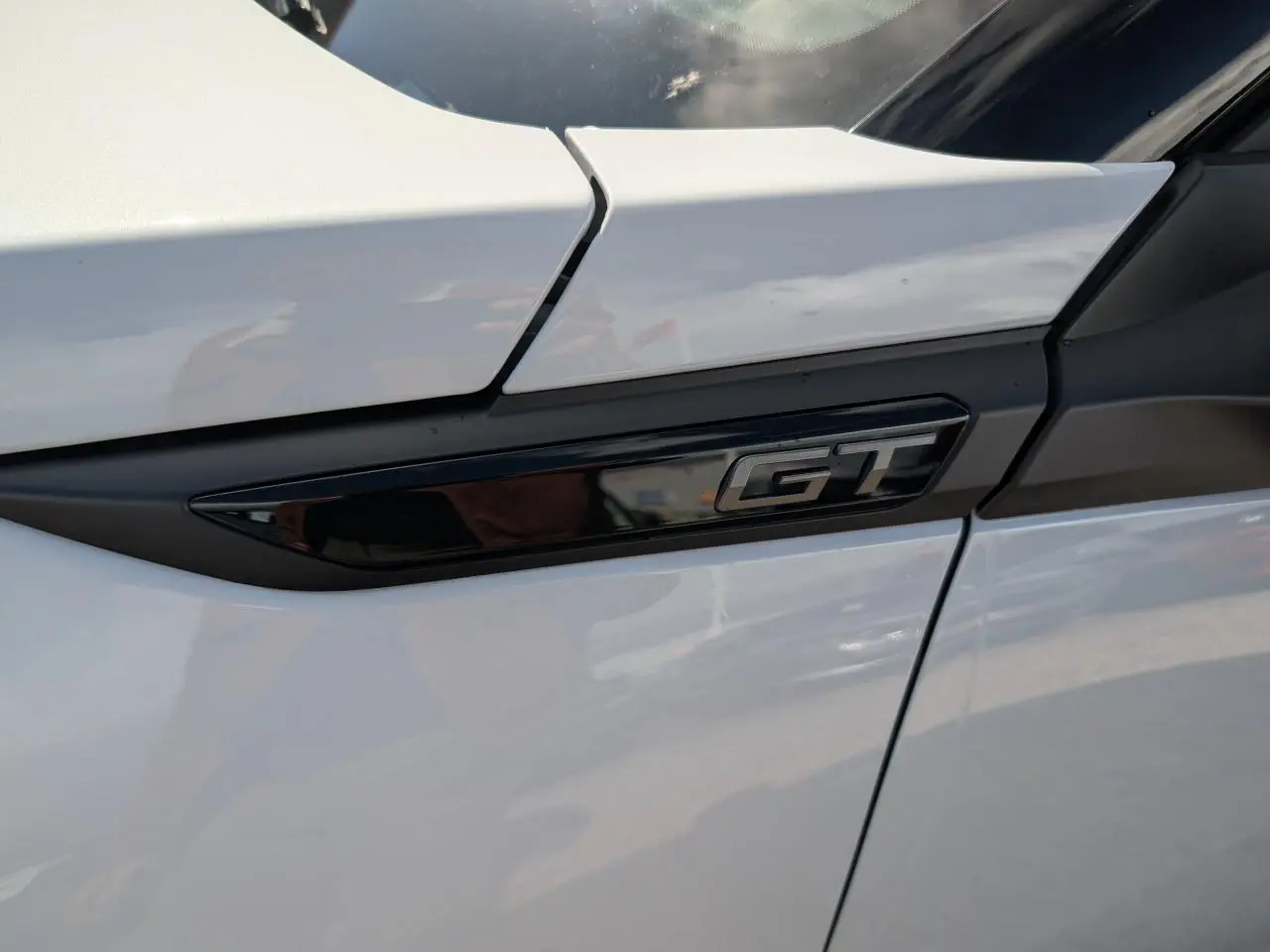 Gros plan sur l’inscription GT noire brillante sur la porte blanche côté droit du Peugeot 2008 hybride.