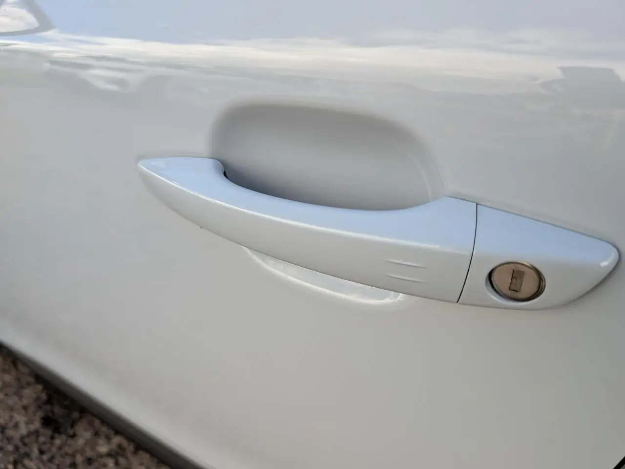 Poignée de porte blanche côté gauche du Peugeot 2008 1.2i Hybrid GT 2026, avec serrure intégrée visible.