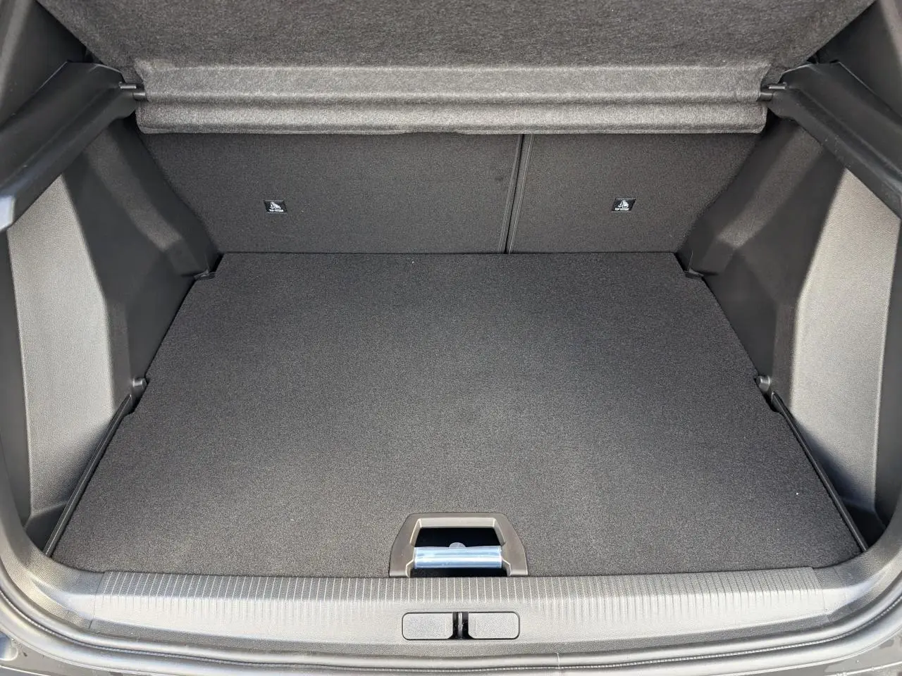 Coffre ouvert du Peugeot 2008 blanc, montrant le plancher plat et la moquette noire intérieure.