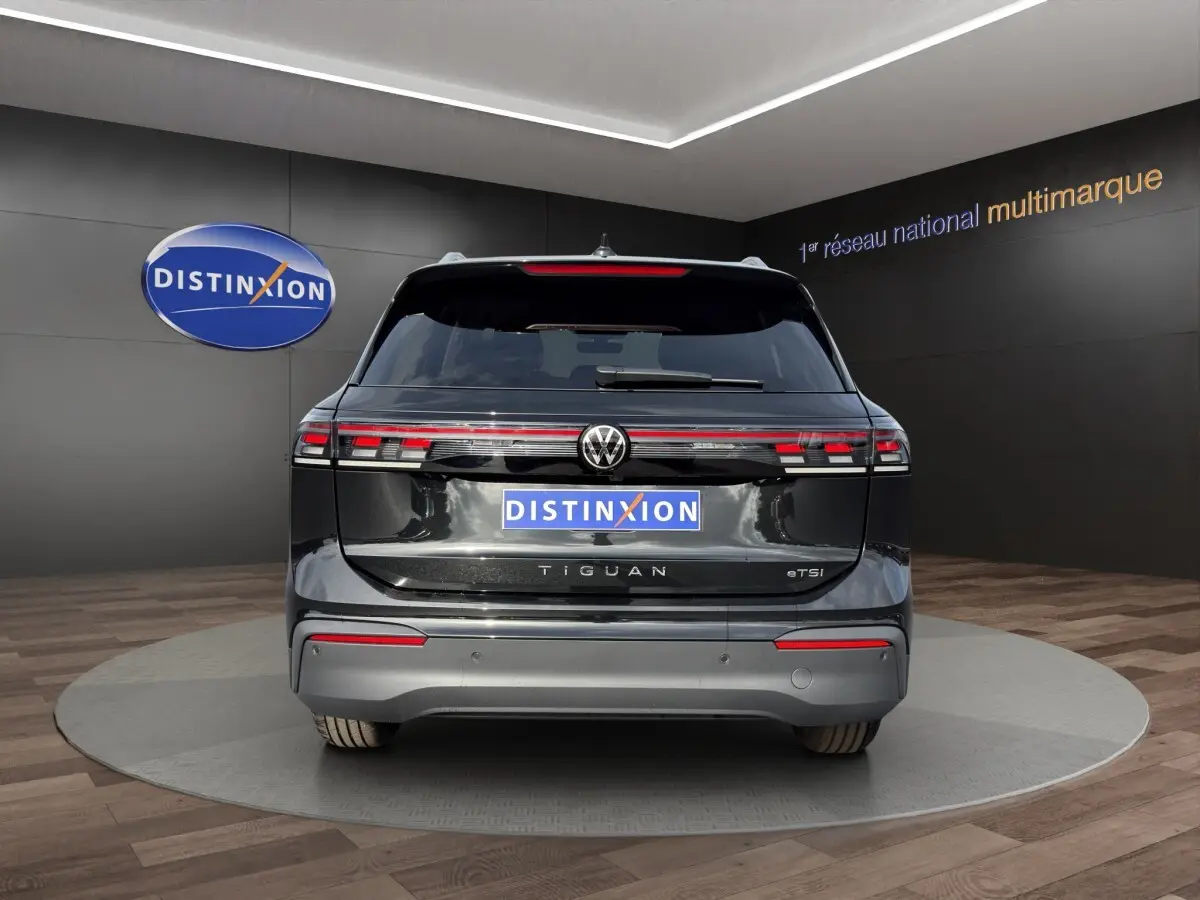 Vue arrière d'un Volkswagen Tiguan noir avec feux arrière LED reliés par une barre lumineuse rouge.