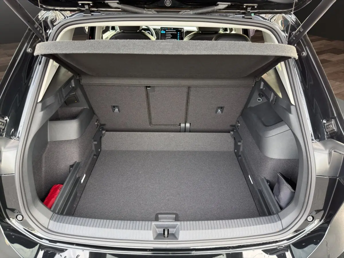 Coffre ouvert vu de l'arrière d'un Volkswagen Tiguan noir 2026, montrant un espace de chargement propre et rangements latéraux.