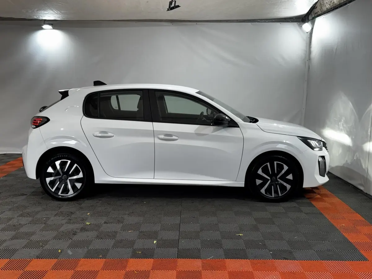 Profil droit de la Peugeot 208 blanche 2024 PureTech 75 S&S Active avec jantes noires et phares LED visibles.