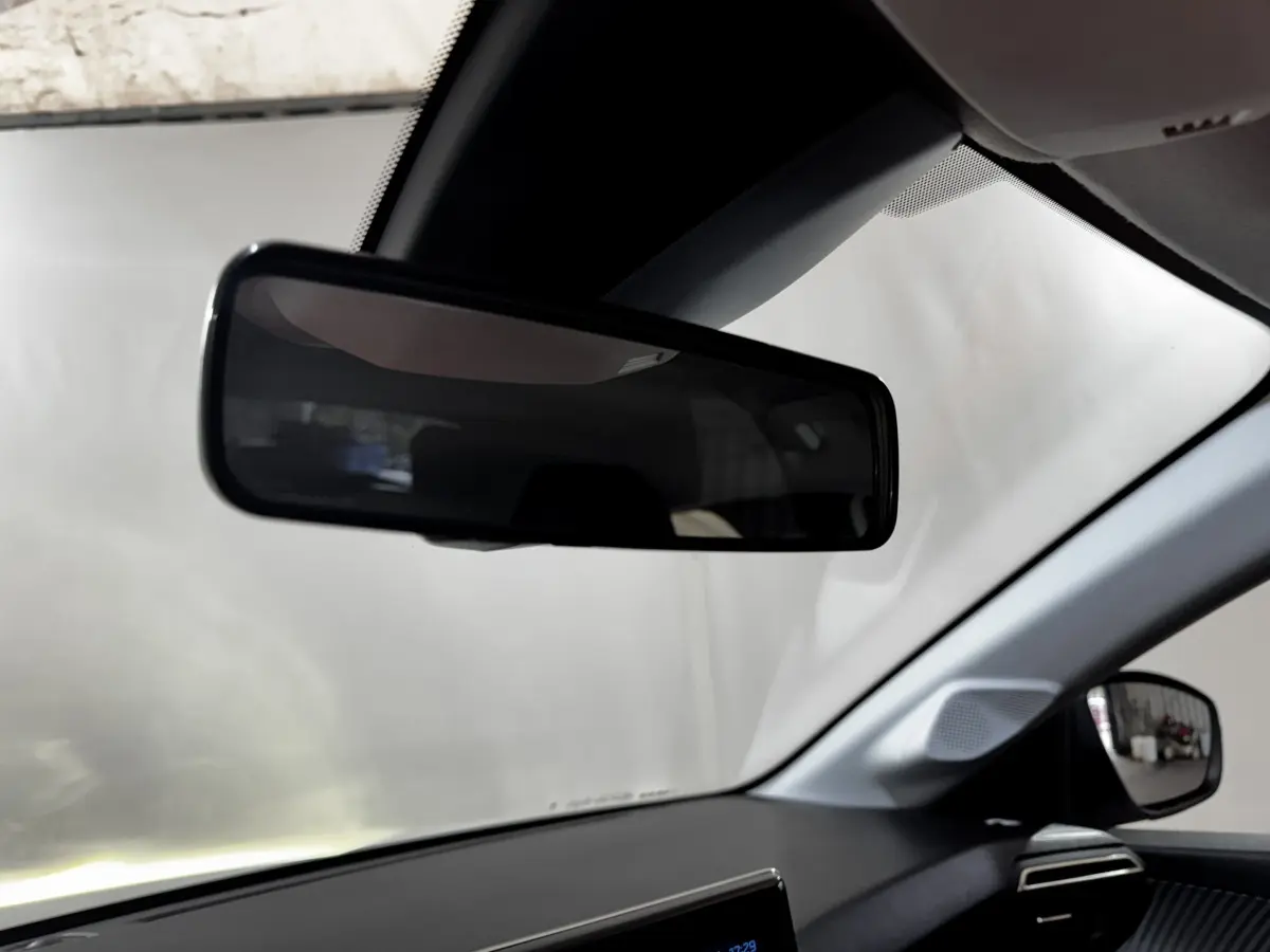 Intérieur de la Peugeot 208 PureTech 75 S&S Active 2024, vue côté conducteur avec rétroviseur et tableau de bord noir.