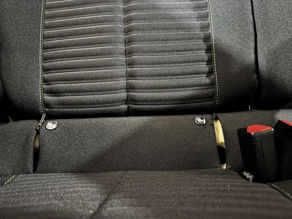 Gros plan sur la banquette arrière noire du Peugeot 208 PureTech 75 S&S Active avec coutures vertes et attaches Isofix visibles.