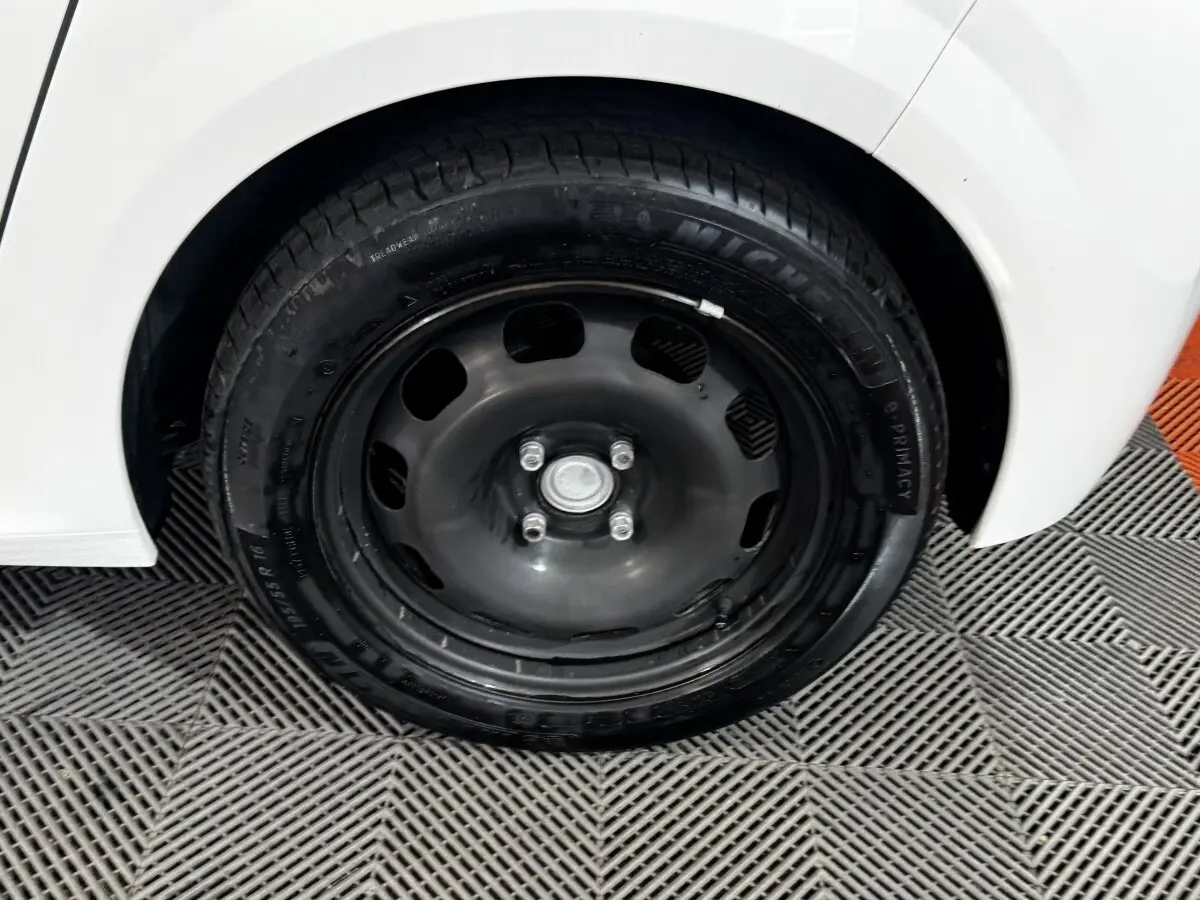 Gros plan sur la roue arrière droite noire de la Peugeot 208 blanche PureTech 75 S&S Active 2024.