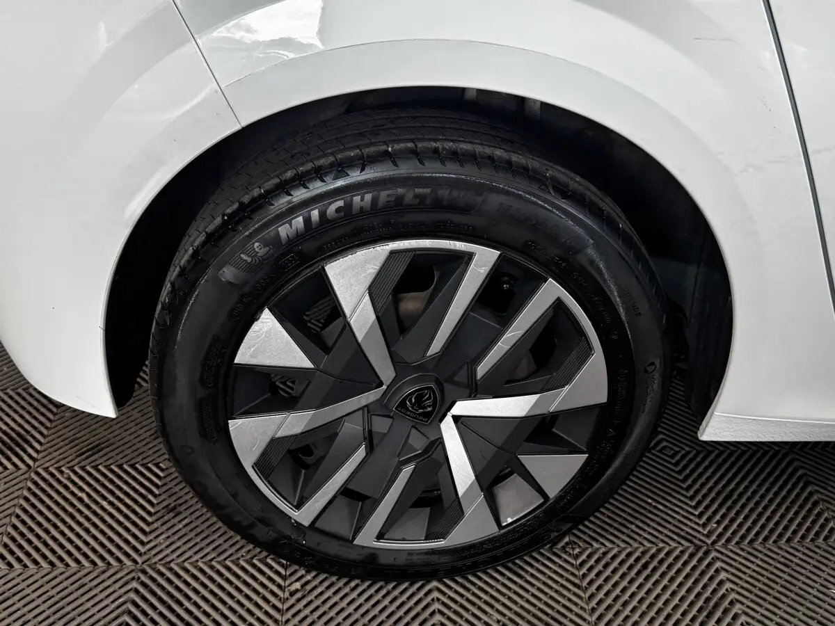 Gros plan sur la roue arrière droite blanche d’une Peugeot 208 PureTech 75 S&S Active avec jante moderne bicolore.