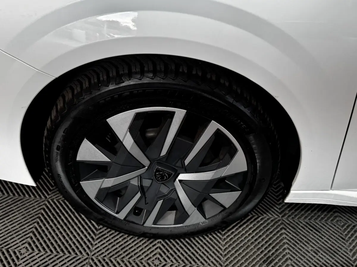 Gros plan sur la roue arrière droite blanche d'une Peugeot 208 PureTech 75 S&S Active avec jante au design moderne.